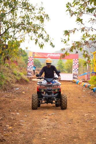 a man riding a four wheeler on a dirt road at Jungle Spring Resort in Ghātkar