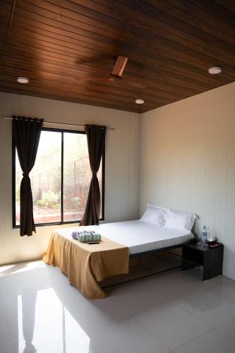 a bedroom with a bed and a large window at Jungle Spring Resort in Ghātkar