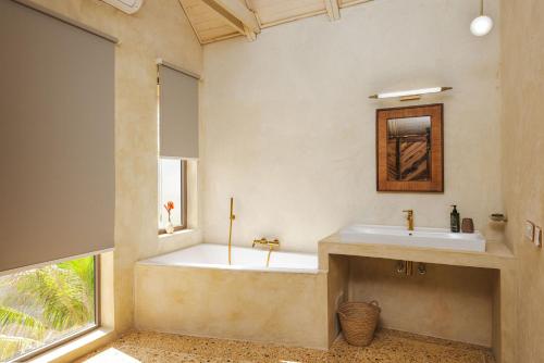a bathroom with a tub and a sink and a window at Clove Island Essence & Spa Boutique in Matemwe