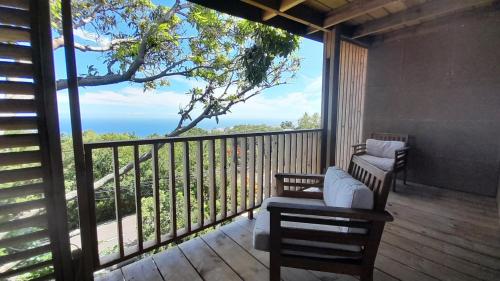 a porch with two chairs and a view of the ocean at Cannelle, T2 Cosy Vue Mer à Mont Vert Les Bas in Saint-Pierre