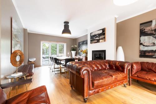a living room with a leather couch and a dining room at Exquisite Townhouse in Lisbon City Center- PRIVATE GARAGE & TERRACE in Lisbon