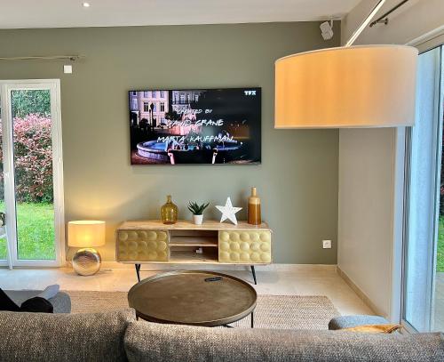 un salon avec un canapé et une télévision sur un mur dans l'établissement La Villa Blanche, à Cavalaire-sur-Mer