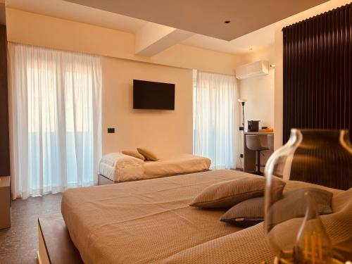 a hotel room with two beds and a flat screen tv at Elegance Rooms Cefalù in Cefalù