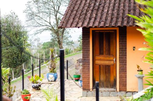a small house with a wooden door and some plants at Pousada Aconchego Shangrilla in Penedo