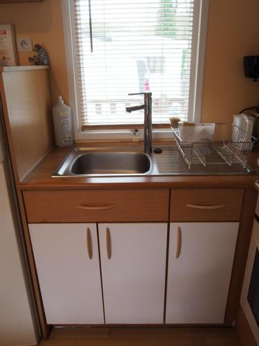 un comptoir de cuisine avec un évier et une fenêtre dans l'établissement Camping Paradis du Quinquis - 4 étoiles - Location estivale en Finistère Sud, à Clohars-Carnoët