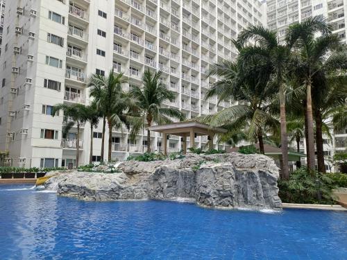 una piscina frente a un gran edificio con palmeras en Pasay Mall of Asia Shore1 Residences Tower C2, en Manila