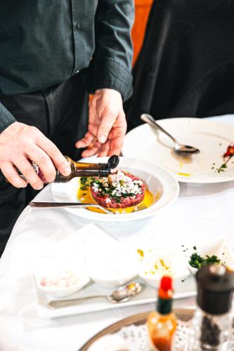a person cutting a plate of food on a table at Logis Hôtel et Restaurant La Bombardière in Cuq-Toulza