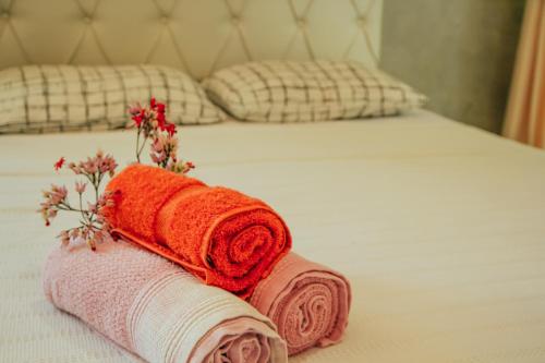 a bed with two towels and flowers on it at Go Pipa INN in Pipa