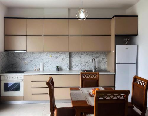 Una cocina con una mesa y un refrigerador blanco. en Liqeni i thate apartment, en Tirana
