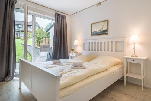 a white bedroom with a large bed and a balcony at Hotel-Restaurant Nordlicht in Kappeln