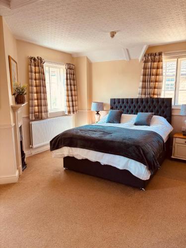 a bedroom with a large bed and two windows at The Sibson Inn Hotel in Water Newton