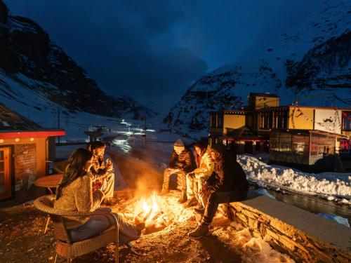 a group of people sitting around a fire at night at Moustache Koksar Luxuria, Sissu in Khoksar