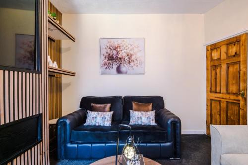 a living room with a blue leather couch at Cosy 3BR Family Home Near Etihad and Coop Live - Free Parking! in Manchester