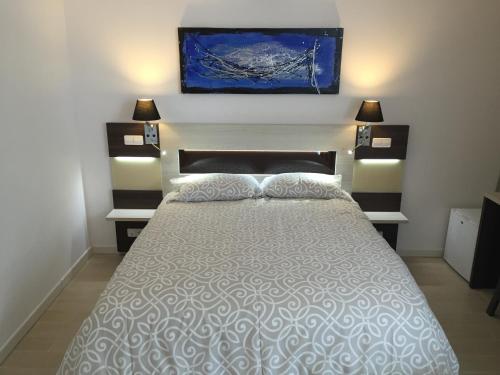 a bedroom with a bed with two lamps and a painting on the wall at H Skyline in Alcorcón