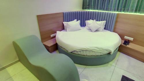 a small bedroom with a bed and a chair at Hotel Grand Acme in Ahmedabad