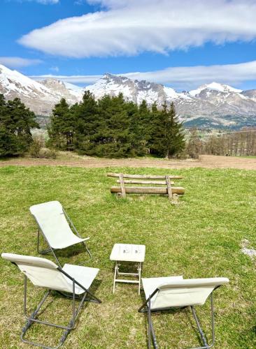 two chairs and a table and a bench in a field at Chalet Joue du loup 6-7 pers in Le Dévoluy