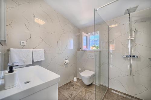a bathroom with a shower and a toilet and a sink at 3rd Floor Apartman in Kaštela
