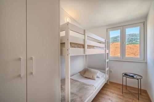 a bedroom with two bunk beds and a window at 3rd Floor Apartman in Kaštela
