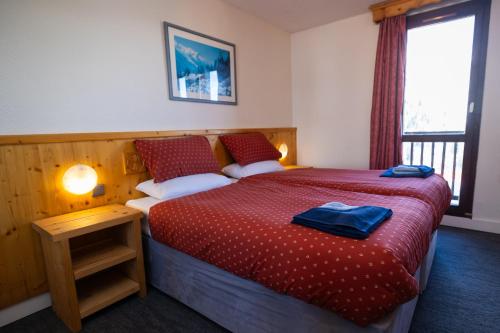 a bedroom with a bed with a red comforter at Hotel l'Aigle in Valmeinier