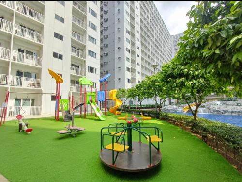 Un área de juegos con un parque infantil en un césped verde en Pasay Mall of Asia Shore1 Residences Tower C2, en Manila