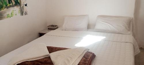 a white bed with white pillows and towels on it at Dana Gardens Hotel in Dana