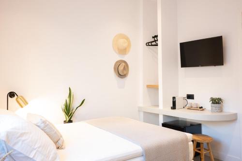 a white bedroom with a bed and a desk at Eleana Hotel in Tinos Town