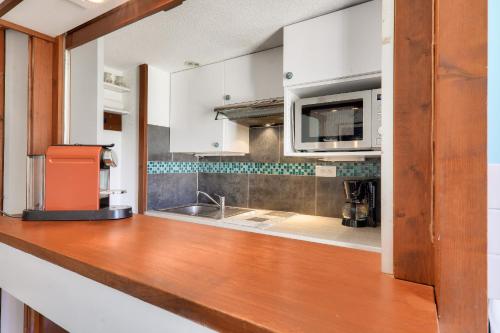a kitchen with white cabinets and a wooden counter top at Idéal 4 adultes et 1 enfant à 300m de la plage in Arzon