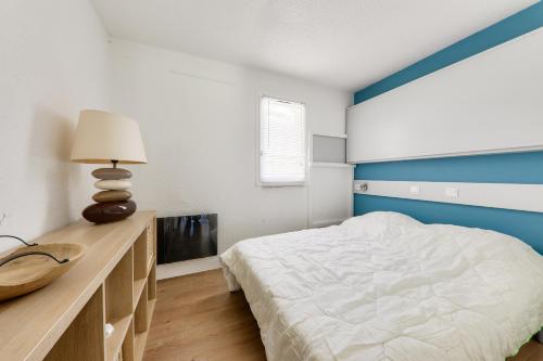 a bedroom with a white bed and a blue headboard at Idéal 4 adultes et 1 enfant à 300m de la plage in Arzon