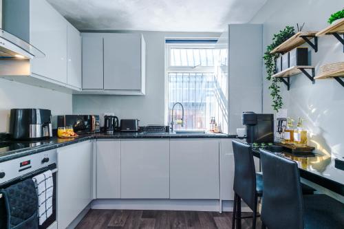 a kitchen with white cabinets and a table with chairs at Stylish & Delightful 3BD Family Home - Near Coop Live & Etihad Stadium - Free Parking - Unlimited high speed WiFi in Manchester