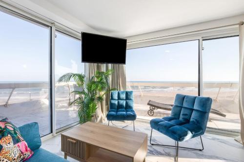 d'un salon avec des chaises bleues et une grande fenêtre. dans l'établissement Ibiza Heliopolis, au Cap d'Agde