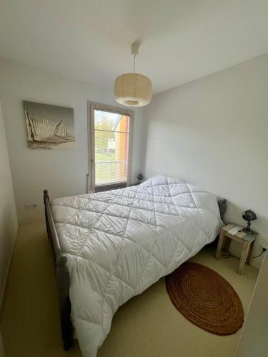 a bedroom with a bed with a white comforter and a window at Maison rêv'etang, Cayeux-sur-Mer, Baie de somme in Cayeux-sur-Mer