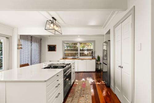 a kitchen with white cabinets and a stove top oven at Bells Beach Bungalow in Clontarf