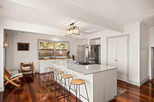 a kitchen with white walls and a bar with stools at Bells Beach Bungalow in Clontarf