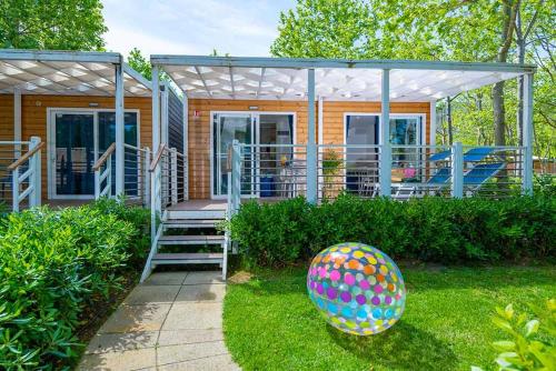 a house with a porch and an egg in the yard at Camping Village Baia Azzurra in Castiglione della Pescaia