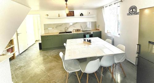 - une cuisine avec une table blanche et des chaises blanches dans l'établissement La Villa Scarlett, à Paluel