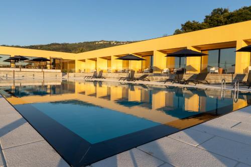 a pool with chairs and umbrellas in front of a building at LOBOS VILLAGE - Alojamento in Seia