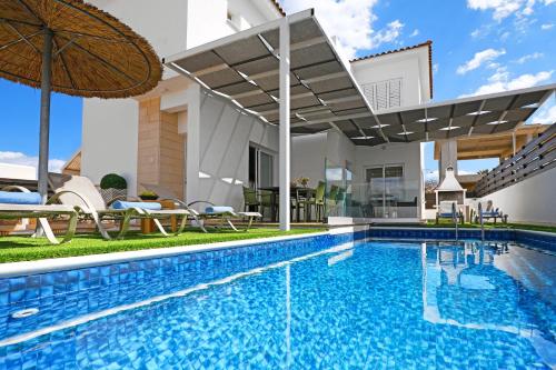 a swimming pool with an umbrella next to a house at Villa White Star - 100m from Serena Beach in Protaras