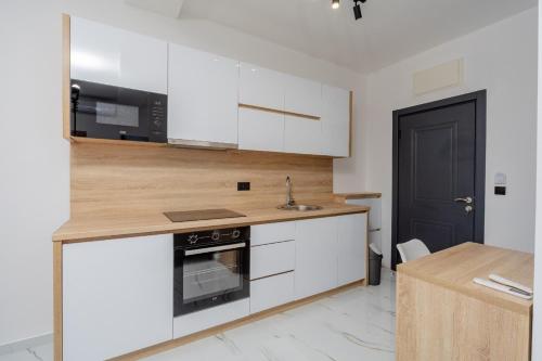 a kitchen with white cabinets and a black door at Aurora Apartments in Bar
