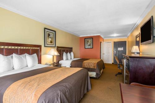 a hotel room with two beds and a flat screen tv at Quality Inn & Suites Bell Gardens-Los Angeles in Bell Gardens