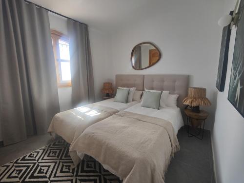 a bedroom with two beds with white sheets and a mirror at AP417 Los Mandarinos in El Molino