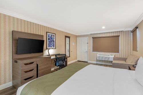 a hotel room with a bed and a flat screen tv at Quality Inn & Suites Anaheim Maingate in Anaheim