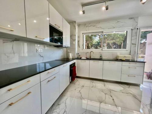 - une cuisine avec des placards blancs et un sol en marbre dans l'établissement 90 m2, 5 min walk to Croisette, Basse Californie, à Cannes