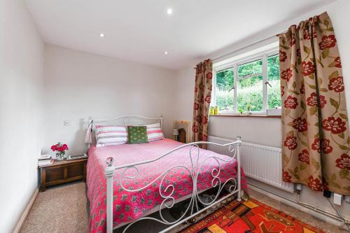 een slaapkamer met een bed en een raam met gordijnen bij Oakleaves in Lodsworth