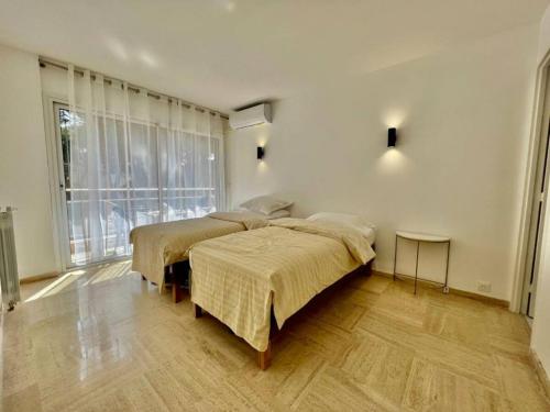 une chambre avec deux lits et une grande fenêtre dans l'établissement 90 m2, 5 min walk to Croisette, Basse Californie, à Cannes