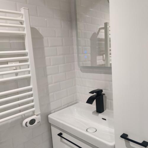 une salle de bain blanche avec un lavabo et un miroir dans l'établissement Studio 83, à Caen