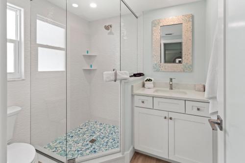 a white bathroom with a shower and a sink at Siesta Key Island Rentals in Siesta Key