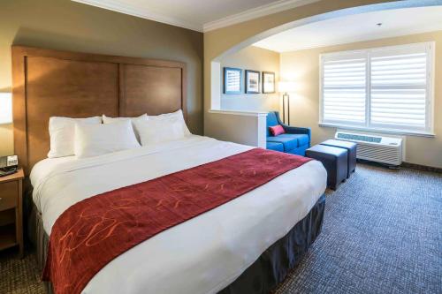a hotel room with a large bed and a chair at Comfort Suites Fresno River Park in Fresno