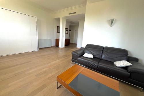 un salon avec un canapé en cuir noir et une table dans l'établissement JUAN LES PINS 6 people pool tennis, à Juan-les-Pins