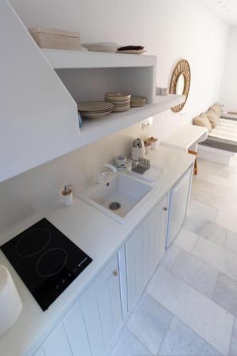 a white kitchen with a sink and a counter at Ammos Studio Pyrgaki Naxos in Agiassos