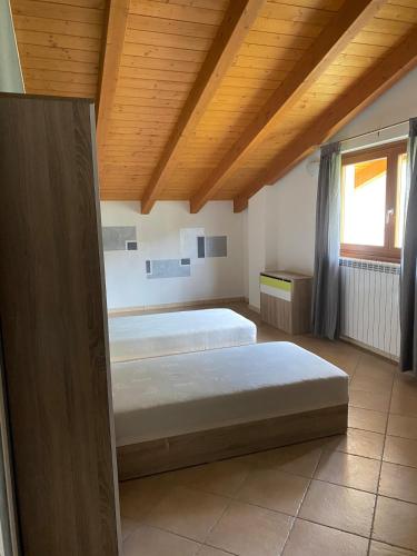 a bedroom with two beds and a wooden ceiling at Elegance Mountain Attic with sauna Edolo Ponte di Legno in Edolo